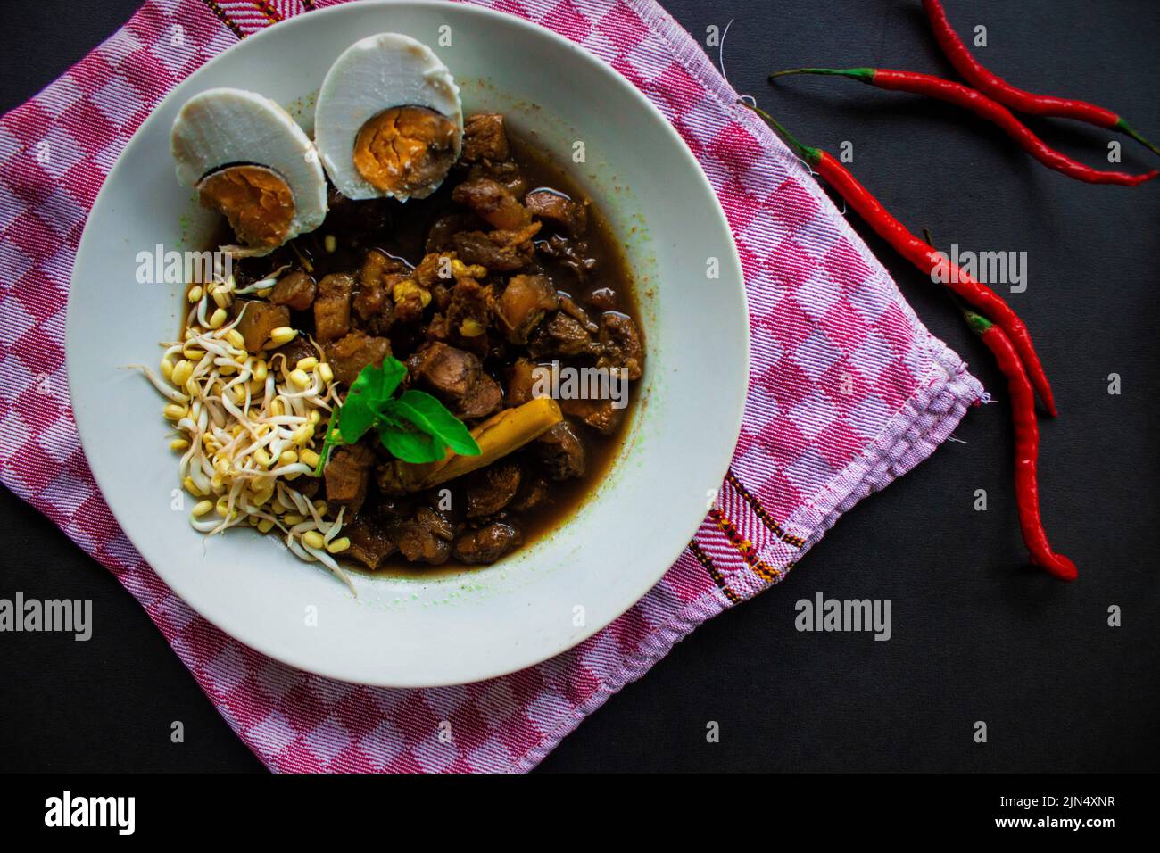 Rawon ou Nasi Rawon/Rawon Rice est une soupe noire traditionnelle de bœuf indonésien servie avec des pousses, des œufs salés et de l'assaisonnement au kluwek. De l'est de Java. Isolé Banque D'Images