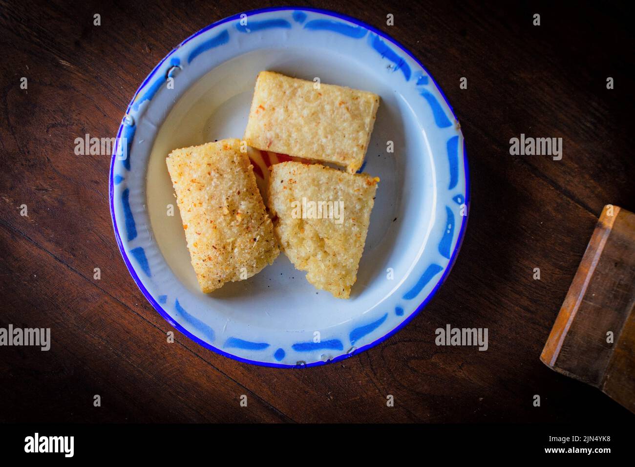 Le jadah goreng ou le gâteau de riz collant frit servi assiette en émail. Sur fond de bois Banque D'Images