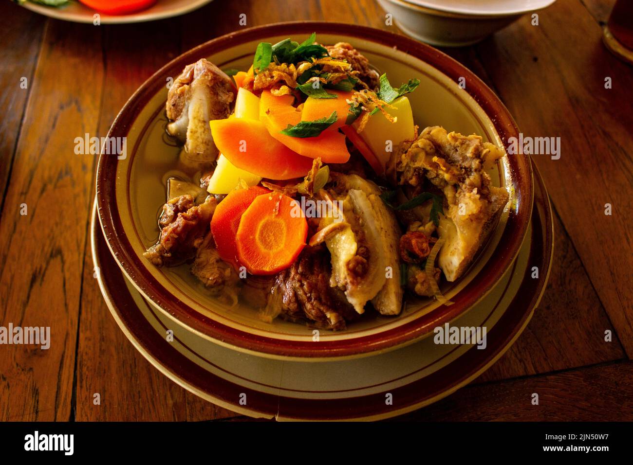 Délicieuse soupe de côtes ou soupe IGA dans un bol servi avec des carottes de pommes de terre et du céleri sur fond de bois Banque D'Images