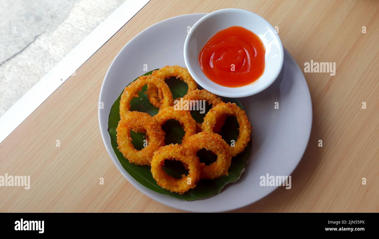 rondelles d'oignon croquantes et sauce tomate servies sur fond de bois Banque D'Images