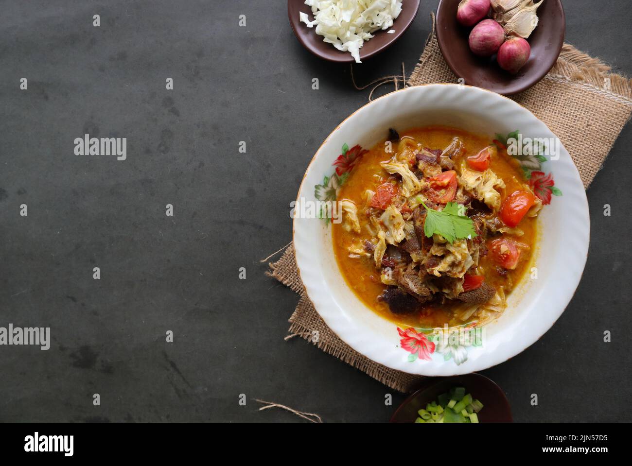 'Curry de chèvre ou kambing gulai, nourriture de l'asie. Délicieux curry de viande de chèvre servi en bowl.served avec tomate, assaisonnement, céleri et chou Banque D'Images