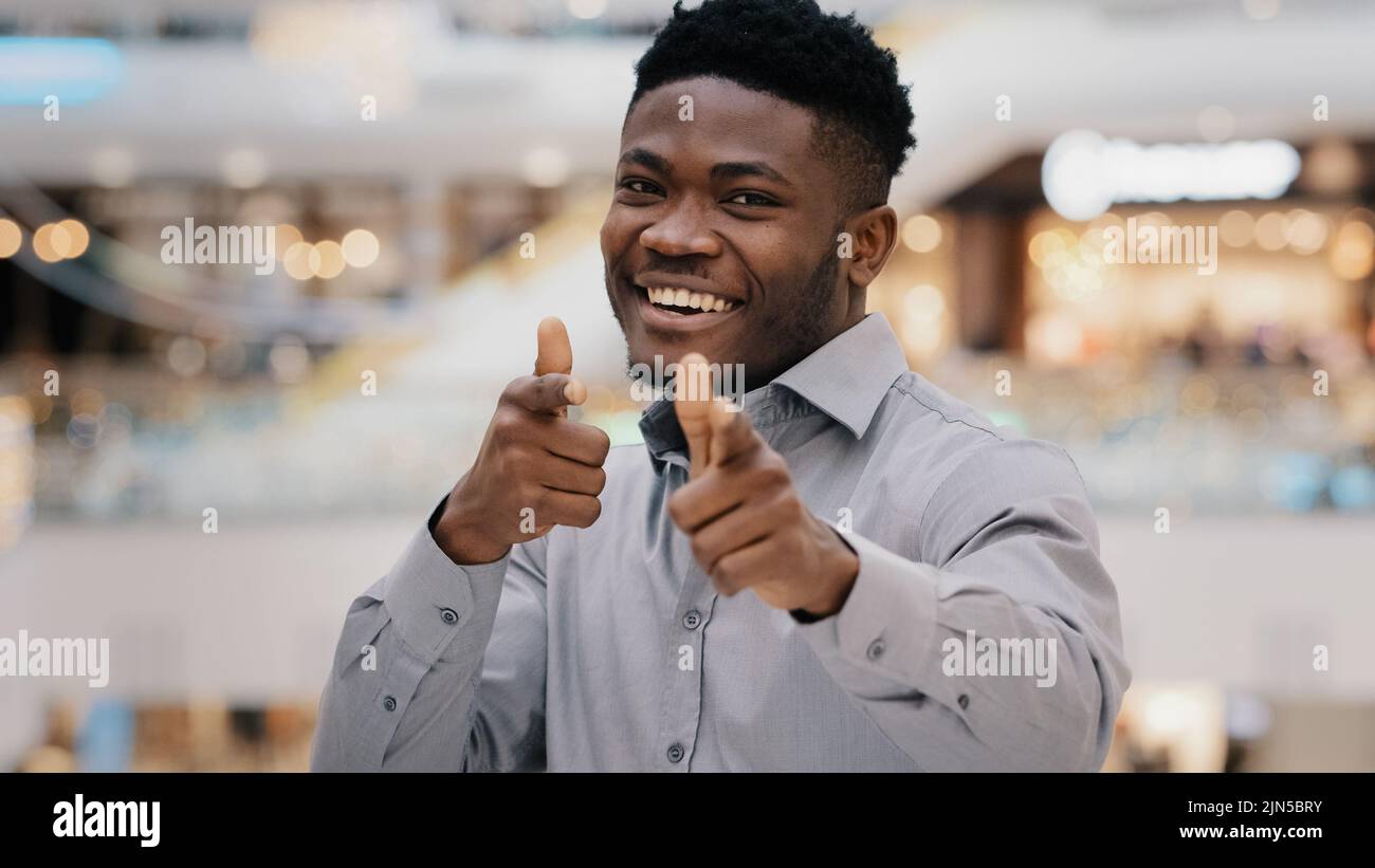 Gros plan joyeux jeune afro-américain beau regardant la caméra souriant posant montrant geste hey you pistolets faisant le choix signe d'approbation Banque D'Images