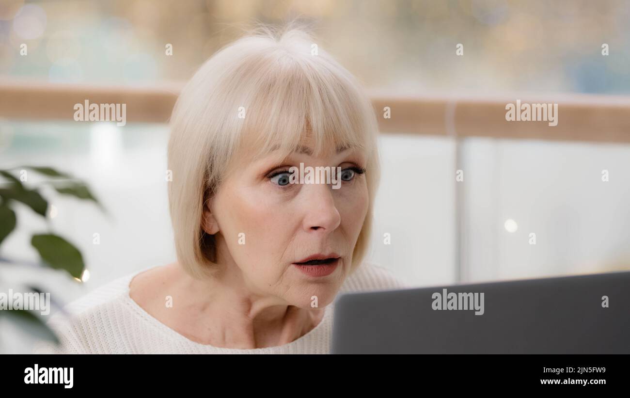 Gros plan surprise excitée femme mûre regardant l'écran d'ordinateur portable d'âge moyen femme d'affaires caucasienne utilisateur lisant de mauvaises nouvelles sur l'accès à Internet Banque D'Images