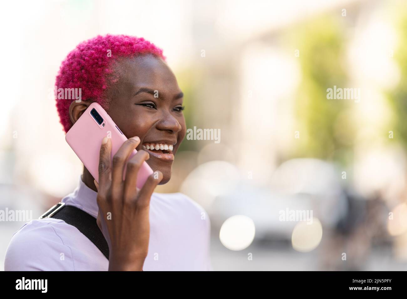 Femme africaine élégante souriant lors de discussions avec les mobiles en extérieur Banque D'Images