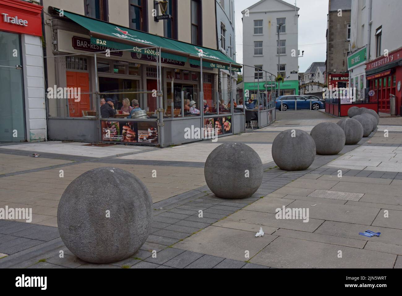 Les gens se sont assis à des tables à l'extérieur des pubs traditionnels irlandais sur la place de Dominick Street, Tralee, County Kerry, Irlande, juillet 2022 Banque D'Images