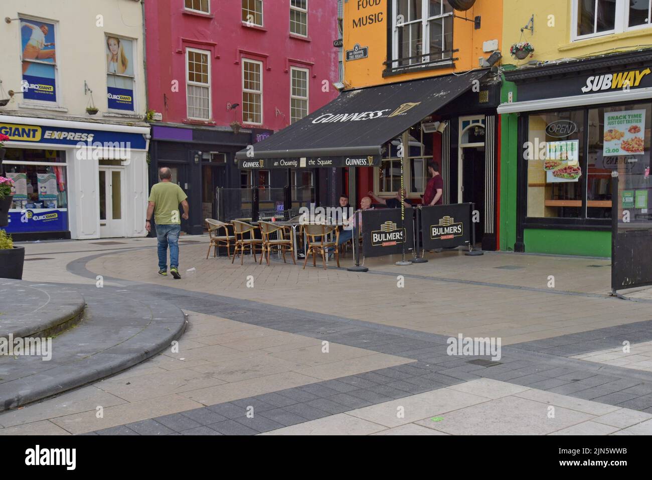 Les gens se sont assis à des tables à l'extérieur des pubs traditionnels irlandais sur la place de Dominick Street, Tralee, County Kerry, Irlande, juillet 2022 Banque D'Images