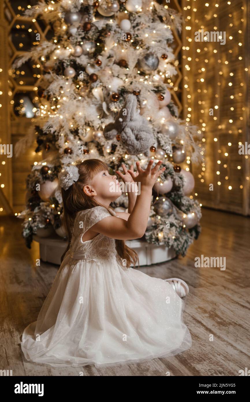Une fille dans une robe de lumière festive à côté d'un arbre de Noël, des  lumières de guirlandes en arrière-plan. Le concept de vacances du nouvel an  Photo Stock - Alamy