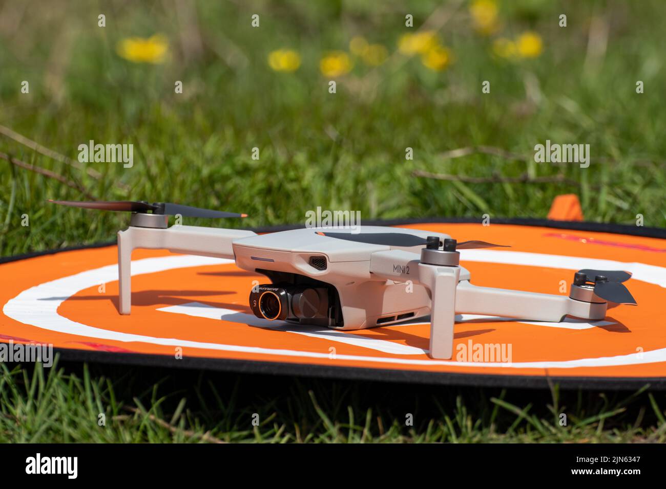 Kharkiv, Ukraine - 22 avril 2021: DJI Mavic Mini 2 drone avec cpl Lens filter sur plate-forme d'atterrissage orange. Quadcopter sur le tapis d'amorce pliable sur le vert Banque D'Images