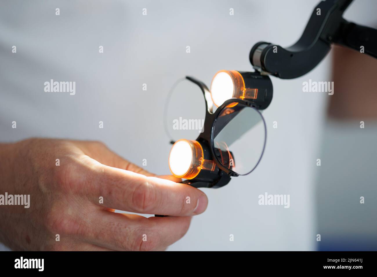 Vue rapprochée des mains des dentistes avec des lunettes à lamelles binoculaires chirurgicales Banque D'Images