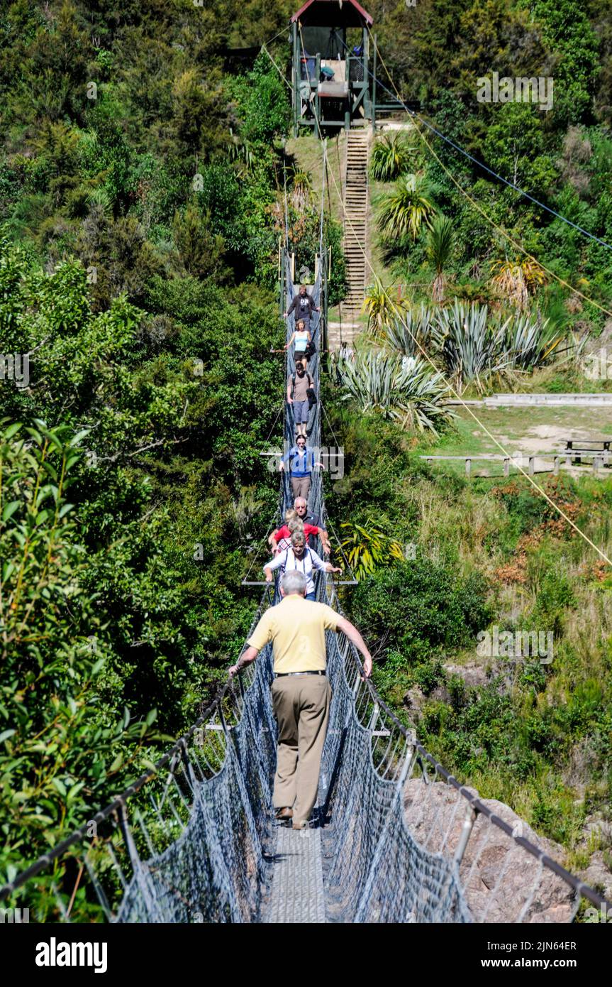 Circulation à deux sens tandis que les visiteurs traversent le plus long pont d'oscillation de Nouvelle-Zélande, au-dessus de la rivière Buller, dans le parc d'attractions et de patrimoine Buller gorge, près de Murchi Banque D'Images