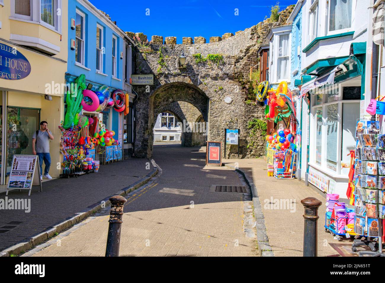 Boutiques de seau et de bêches colorées à côté des murs de la vieille ville historique de Five Arches dans St George's Street, Tenby, Pembrokeshire, pays de Galles, Royaume-Uni Banque D'Images