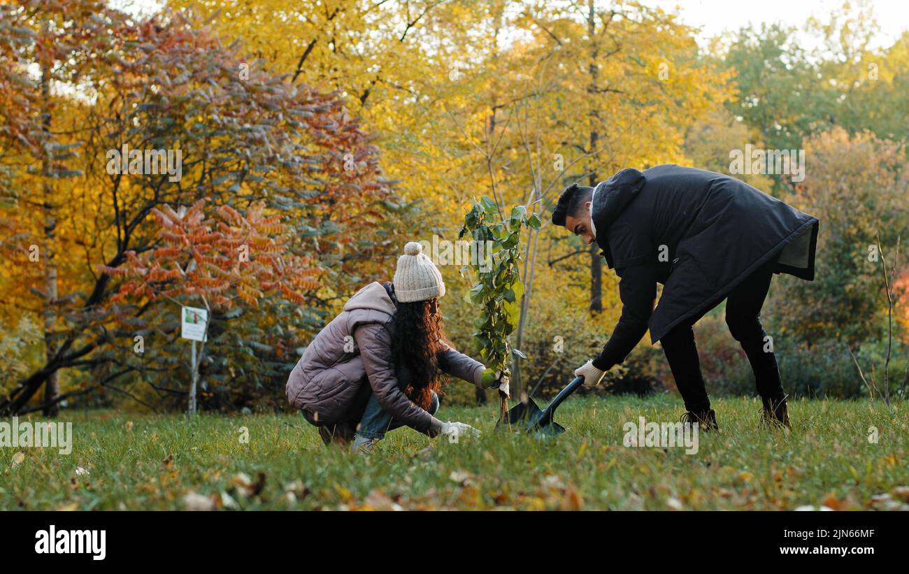 Les jeunes couple gars et filles éco-activistes plantent arbre dans le parc engagé dans l'aménagement forestier prennent soin de la nature environnement écologie reboisement profiter Banque D'Images