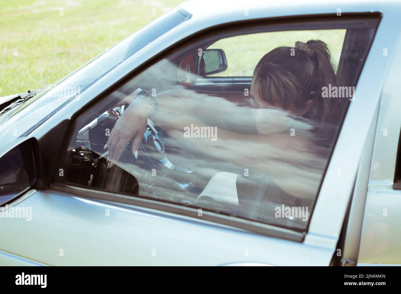 Femme regarde attentivement à travers le verre de voiture avec réflexion Banque D'Images