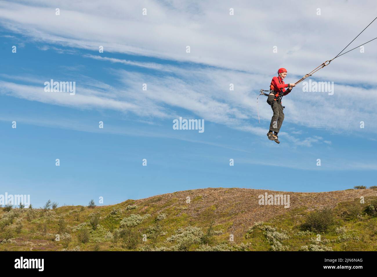 Garçon utilisant une balançoire géante sur le cours d'accès de corde élevé en Islande Banque D'Images