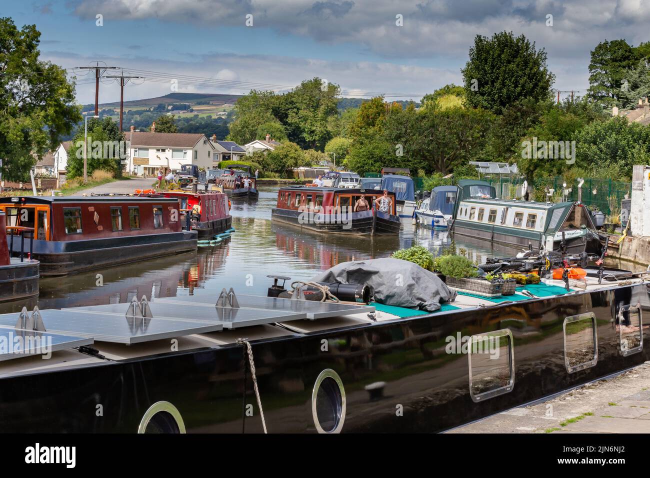 Des barges (bateaux étroits) naviguent le long du canal Leeds Liverpool à Bingley, dans le West Yorkshire. D'autres sont amarrés. Ceci se trouve au-dessus des cinq verrous de montée. Banque D'Images