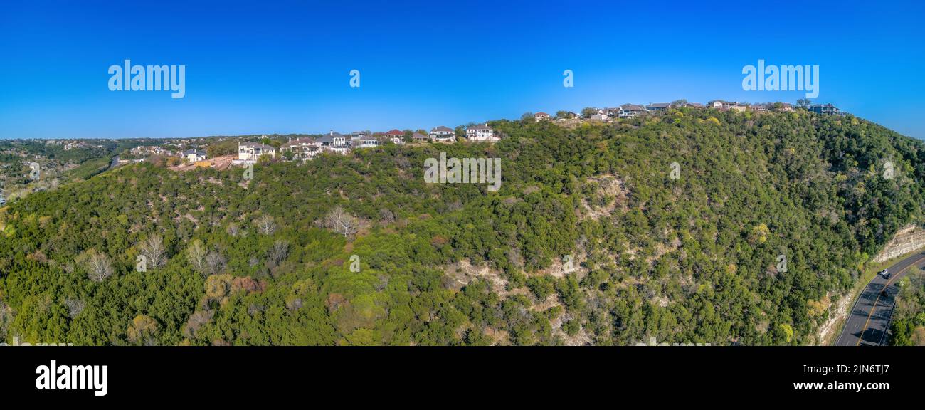 Austin. Texas - vue panoramique sur les demeures et les villas en haut d'une pente contre le ciel bleu clair. Il y a une route sur la droite en bas Banque D'Images