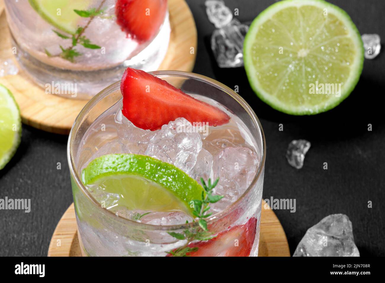 Cocktail mojito aux fraises fraîches. Deux verres avec soda aux fraises fraîches d'été avec fraise, glace et citron vert, décoré de thym sur fond foncé Banque D'Images