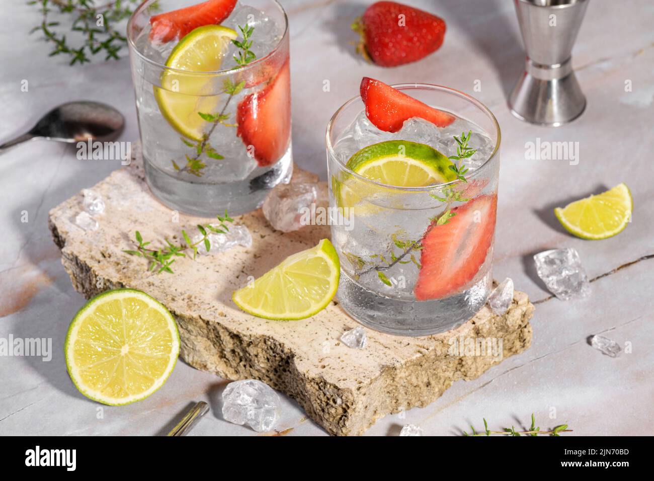 Mojito, margarita, daiquiri. Deux verres avec boisson fraîche au soda aux fraises, glace et outils barman sur le podiu de travertin Banque D'Images