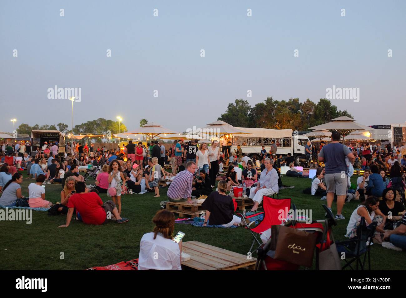 Dubaï, Émirats arabes Unis - 26 mars 2016 : divers groupes de personnes se détendent sur l'herbe pendant le Jam camion alimentaire au club de golf Emirates au crépuscule. Banque D'Images