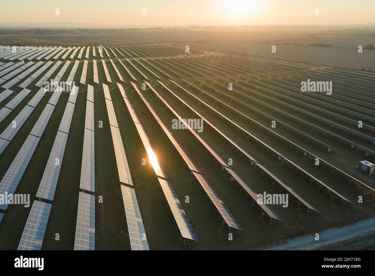 Vue aérienne de la grande centrale électrique durable avec de nombreuses rangées de panneaux photovoltaïques solaires pour produire de l'énergie électrique propre au coucher du soleil Banque D'Images