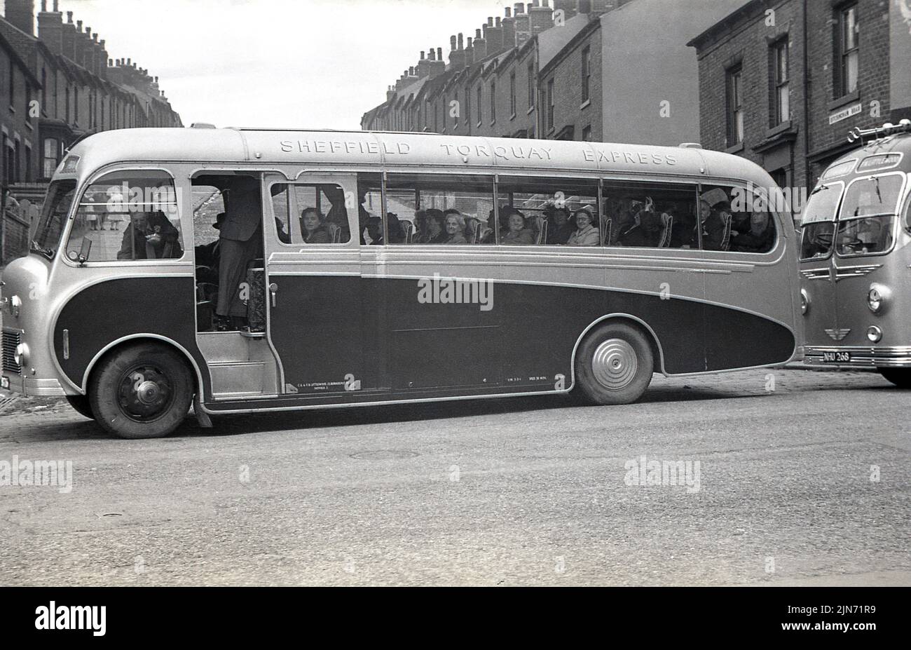 1950s, historique, excursion en autocar, Sheffield-Torquay Express. Passagers assis dans un autocar Littlewood Bros attendant sur Grimesthorpe Road devant l'épicerie Lily Bell, au coin de Ditchingham Road, Sheffield, South Yorkshire, Angleterre, Royaume-Uni. Banque D'Images