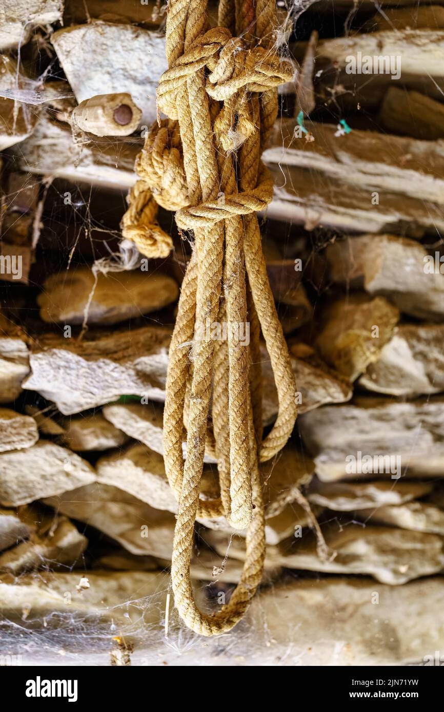 Corde utilisée pour les travaux sur le terrain sur un mur de pierre en état d'abandon au fil des ans. Banque D'Images