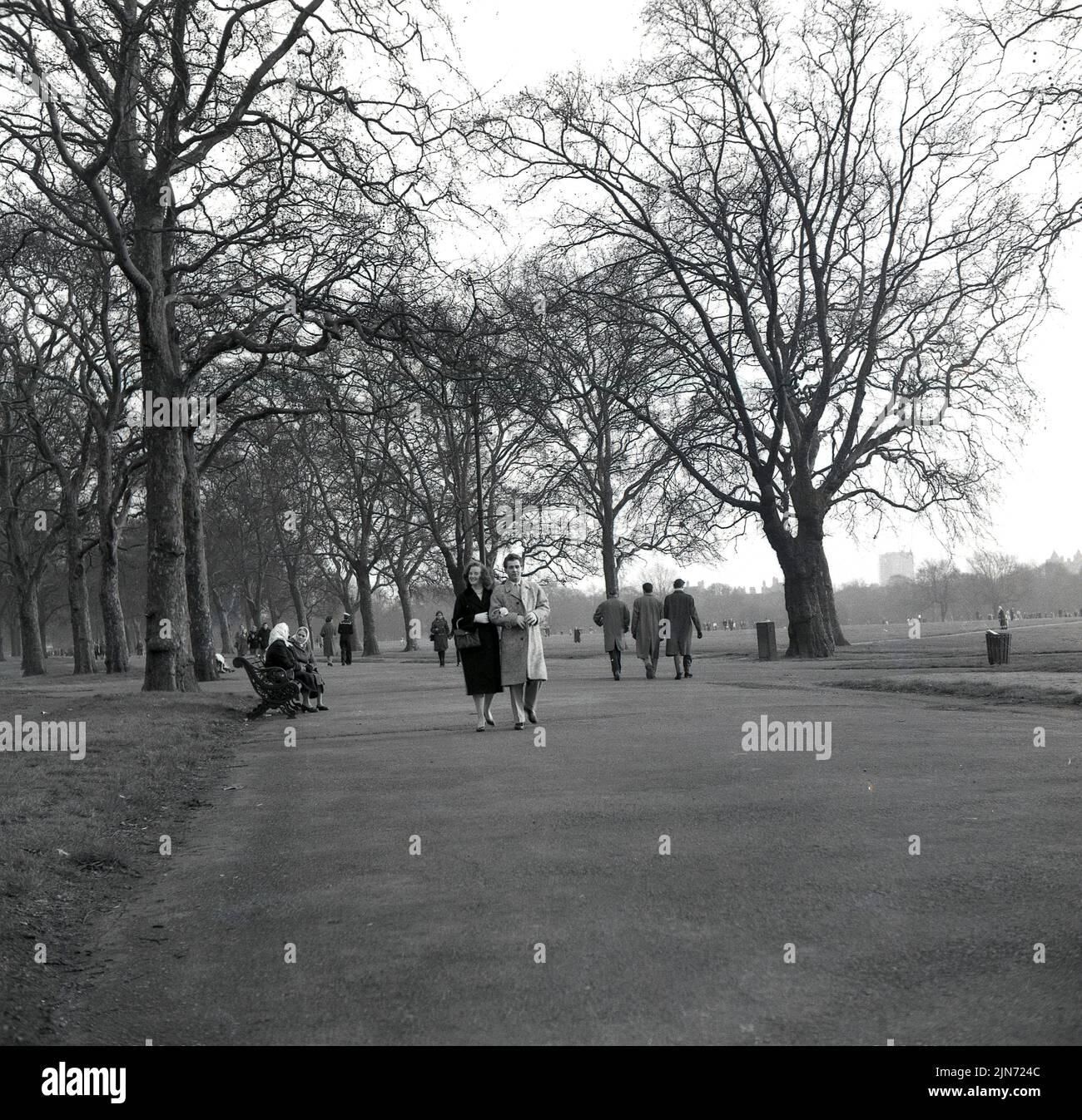 1950s, historique, couple marchant le long d'un chemin dans Hyde Park de Londres, un grand parc royal dans le centre de la ville, Angleterre, Royaume-Uni. Banque D'Images