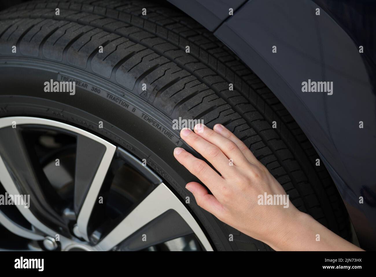 Une femme pilote inspecte les pneus de sa nouvelle voiture. Concept de sécurité du véhicule Banque D'Images