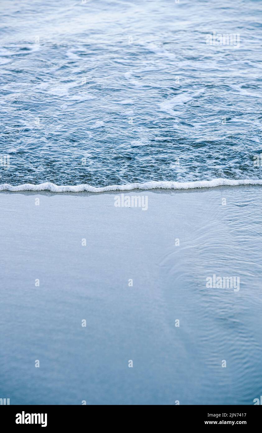 La mer briser doucement sur une plage de sable Banque D'Images