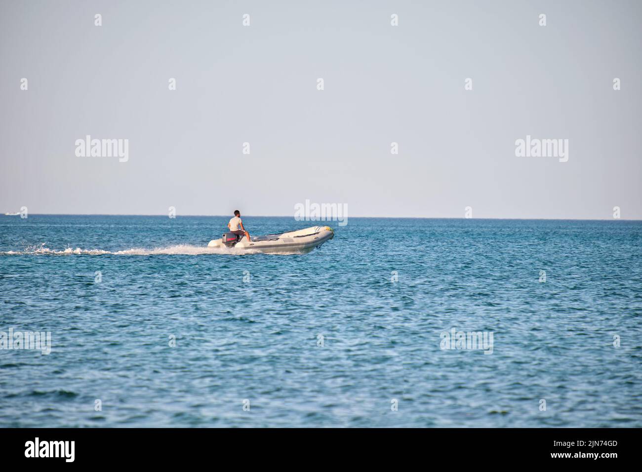 Paysage de mer avec surface ondulée d'eau de mer bleue avec hors-bord blanc nageant rapidement sur des vagues calmes Banque D'Images