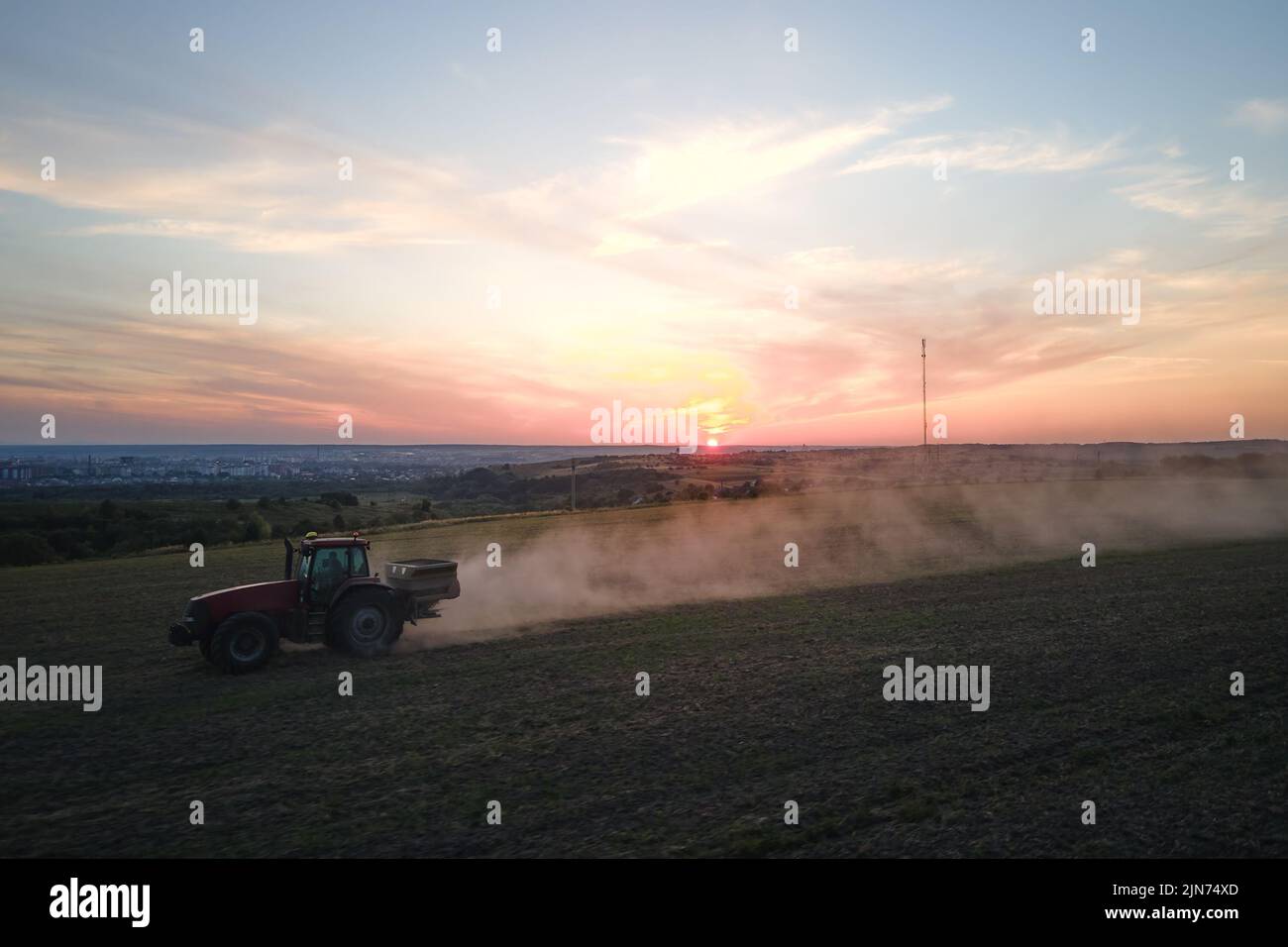 Tracteur pulvérisant des engrais avec des produits chimiques d'herbicide insecticide sur le champ agricole au coucher du soleil Banque D'Images