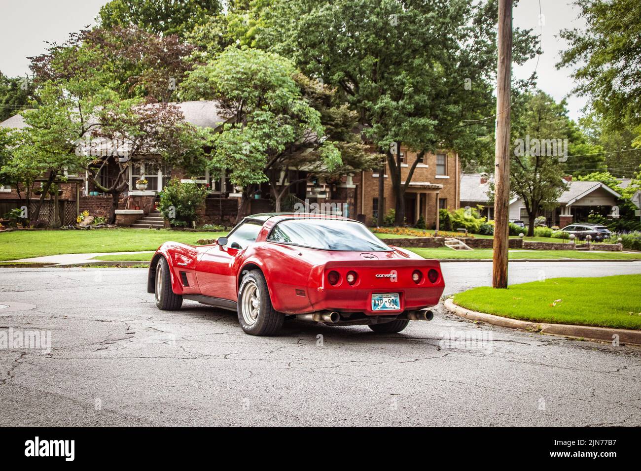 6-9-2022 Tulsa USA - Red Corvette se prépare à tourner à l'intersection dans le quartier résidentiel en été Banque D'Images
