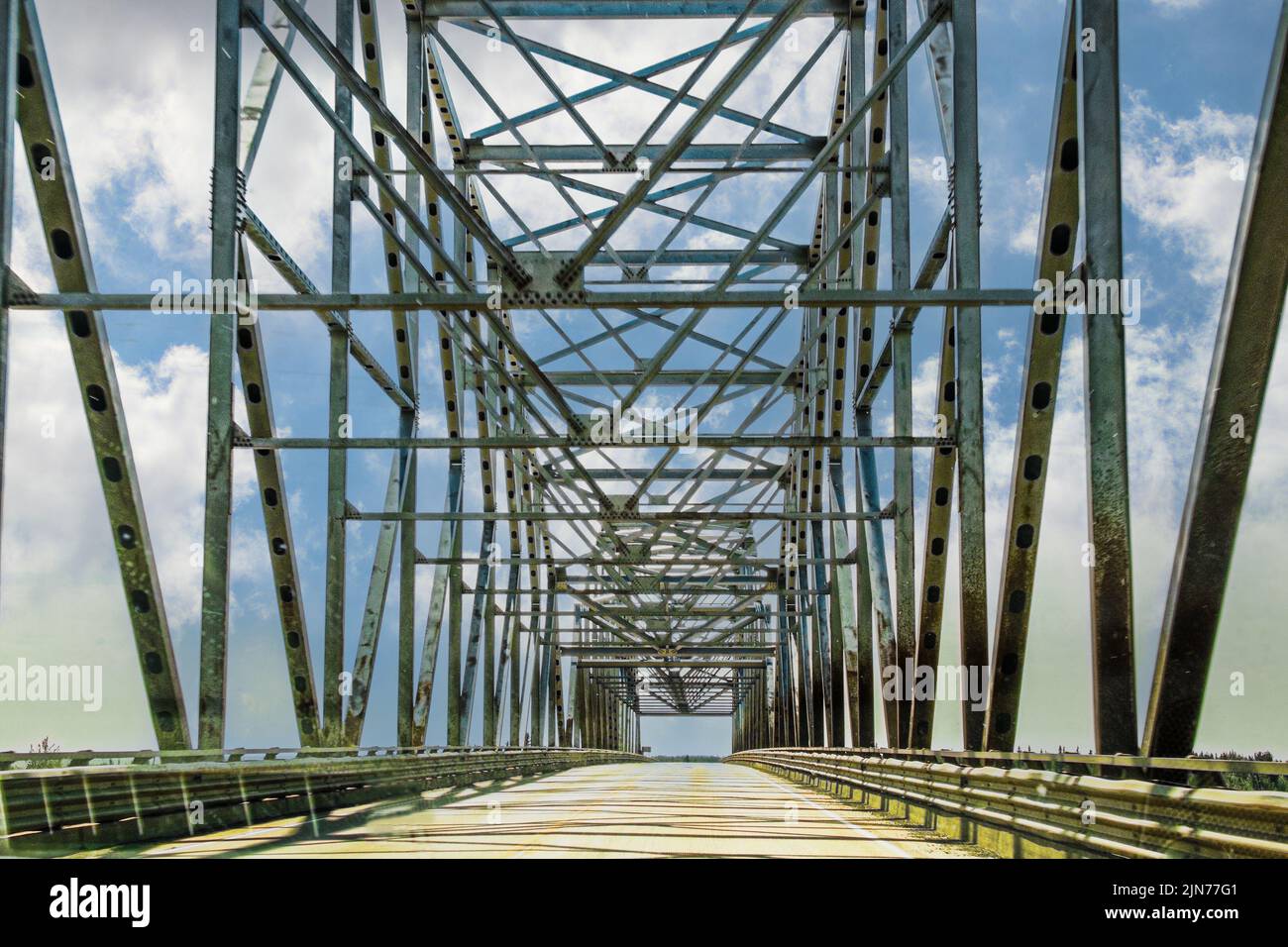 Traversée d'un pont de treillis routier à travées multiples au-dessus d'une rivière avec ciel bleu nuageux Banque D'Images