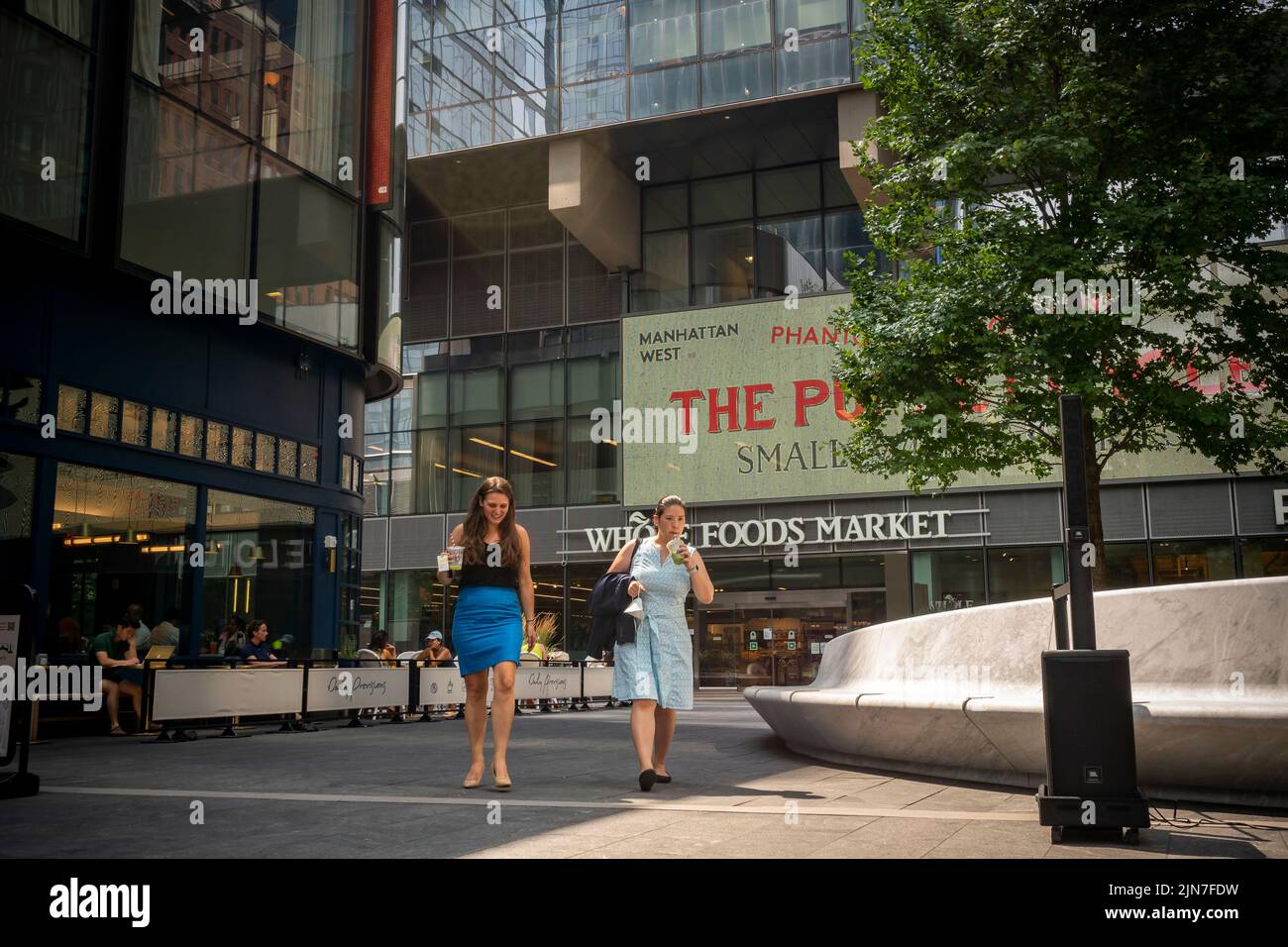 Les employés de bureau avec leurs boissons traversent la place du complexe de Manhattan West à New York jeudi, 28 juillet 2022. (© Richard B. Levine) Banque D'Images