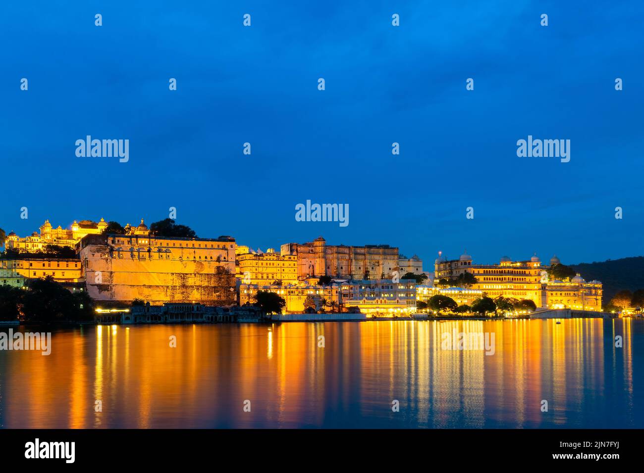 Une vue en soirée du palais d'Udaipur se reflète sur le lac avec un ciel lumineux en arrière-plan Banque D'Images