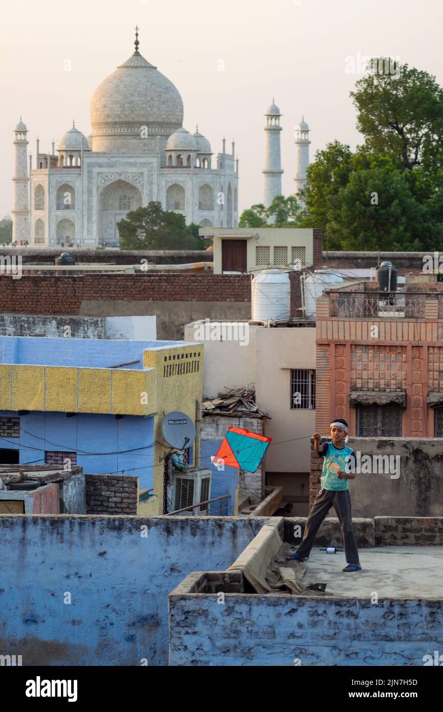 Un cliché vertical d'un enfant jouant avec un cerf-volant sur un toit avec le Taj Mahal en arrière-plan Banque D'Images