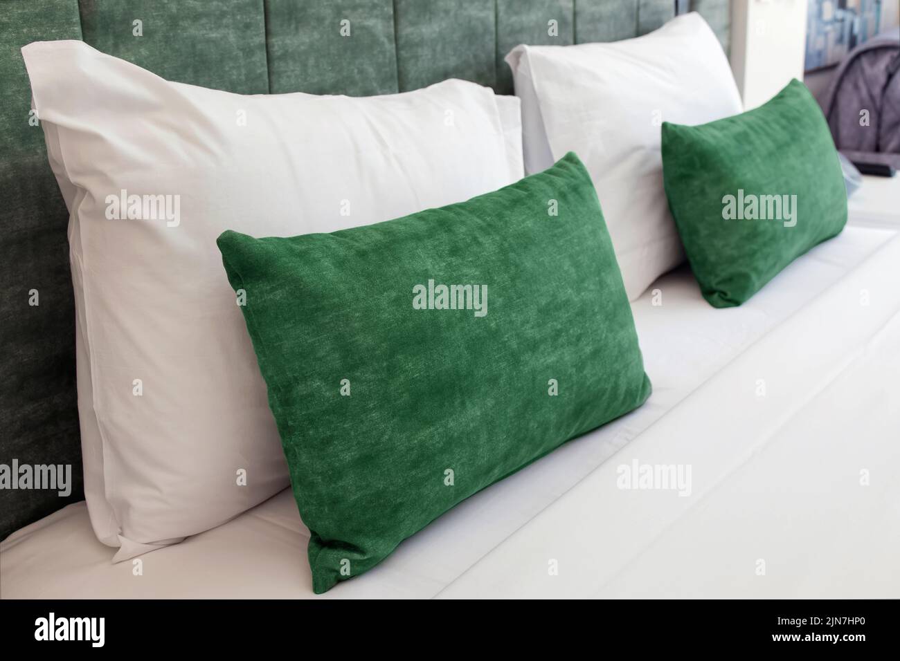Vue rapprochée d'un lit confortable avec oreillers moelleux vert clair et tête de lit Banque D'Images