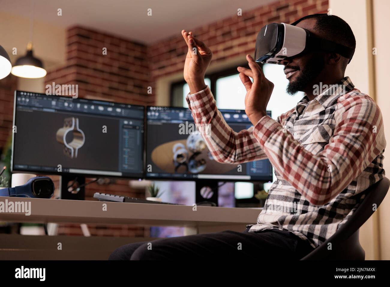 Un développeur afro-américain fabrique des engrenages de moteur à l'aide de lunettes vr avec un logiciel de simulation et de CAO 3D sur ordinateur. Techinican développe des machines industrielles avec des lunettes interactives. Banque D'Images