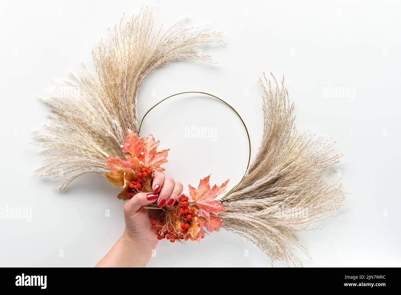 Couronne florale de pampas sec et feuilles d'automne. Les mains noue les décorations au cadre en métal. Banque D'Images