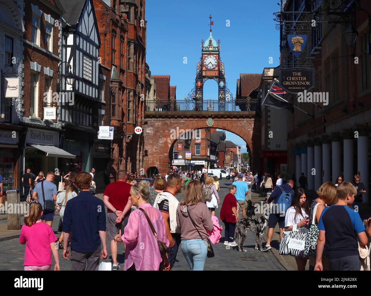 Eastgate, les acheteurs avec la célèbre horloge de la tourelle Eastgate, au-dessus de l'Eastgate des murs anciens de Chester, Cheshire, Angleterre, Royaume-Uni, CH1 1LE Banque D'Images