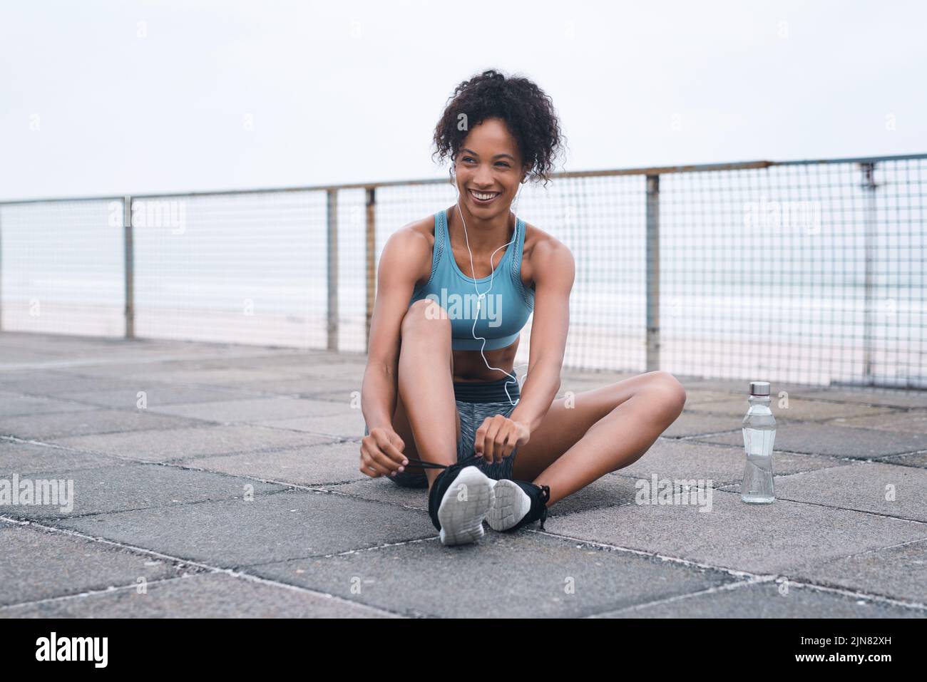 Je vais courir si vite vers mes objectifs. Une jeune femme sportive enfile ses lacets tout en faisant de l'exercice à l'extérieur. Banque D'Images