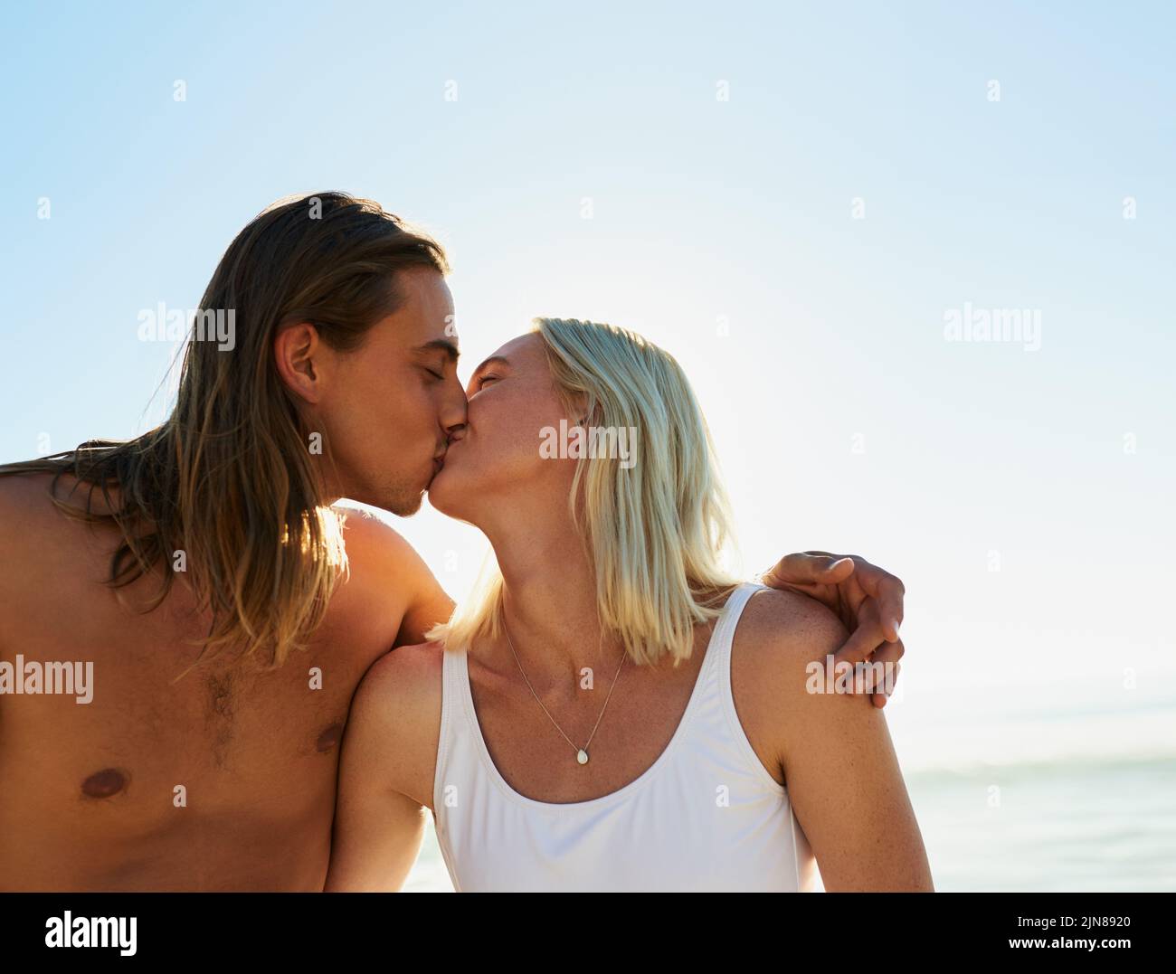Notre amour est tout ce qui compte. Un jeune couple affectueux s'embrassant les uns les autres à la plage. Banque D'Images