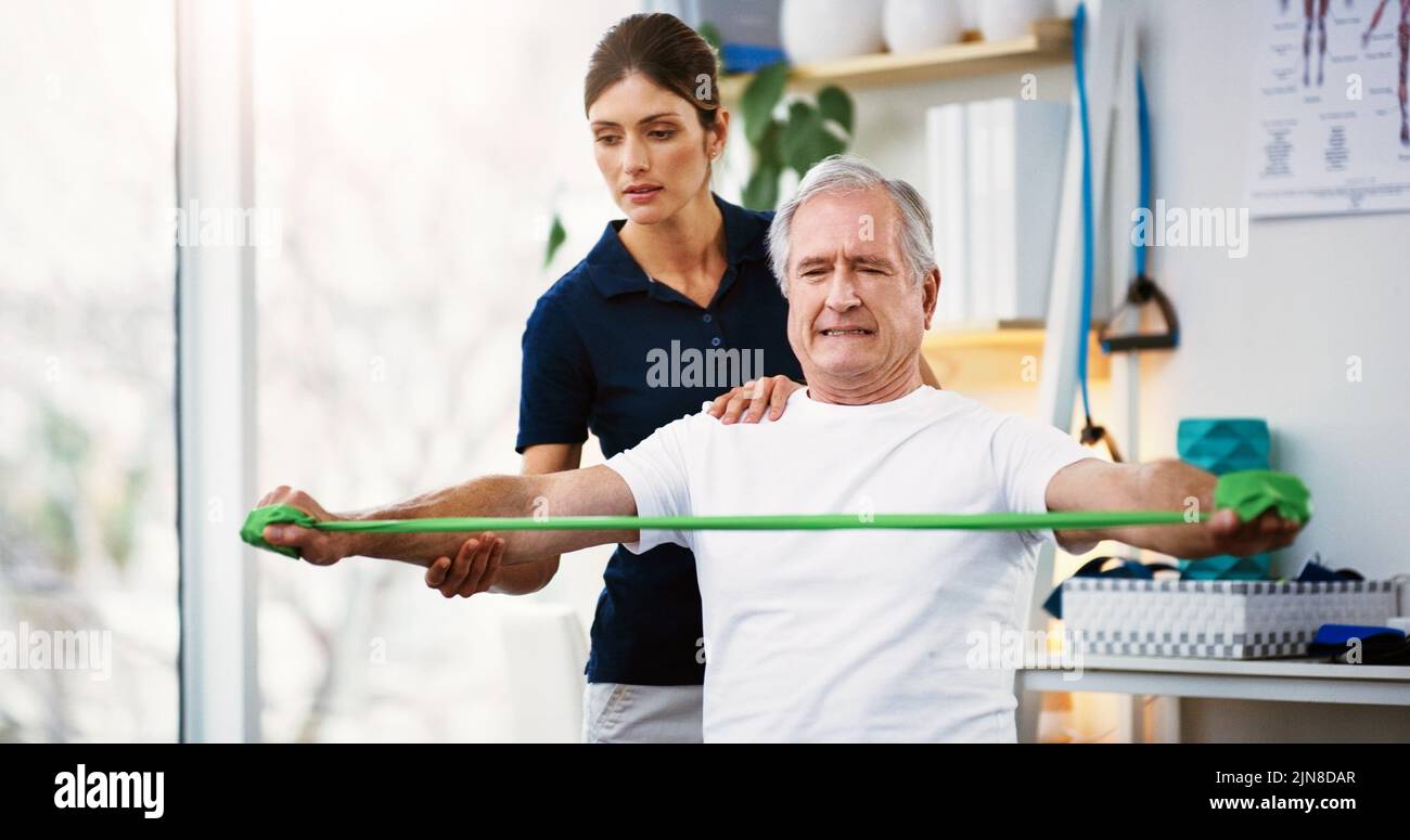 HES travaille dur pour rester actif et en bonne santé. Une jeune femme physiothérapeute attirante travaillant avec un homme âgé. Banque D'Images