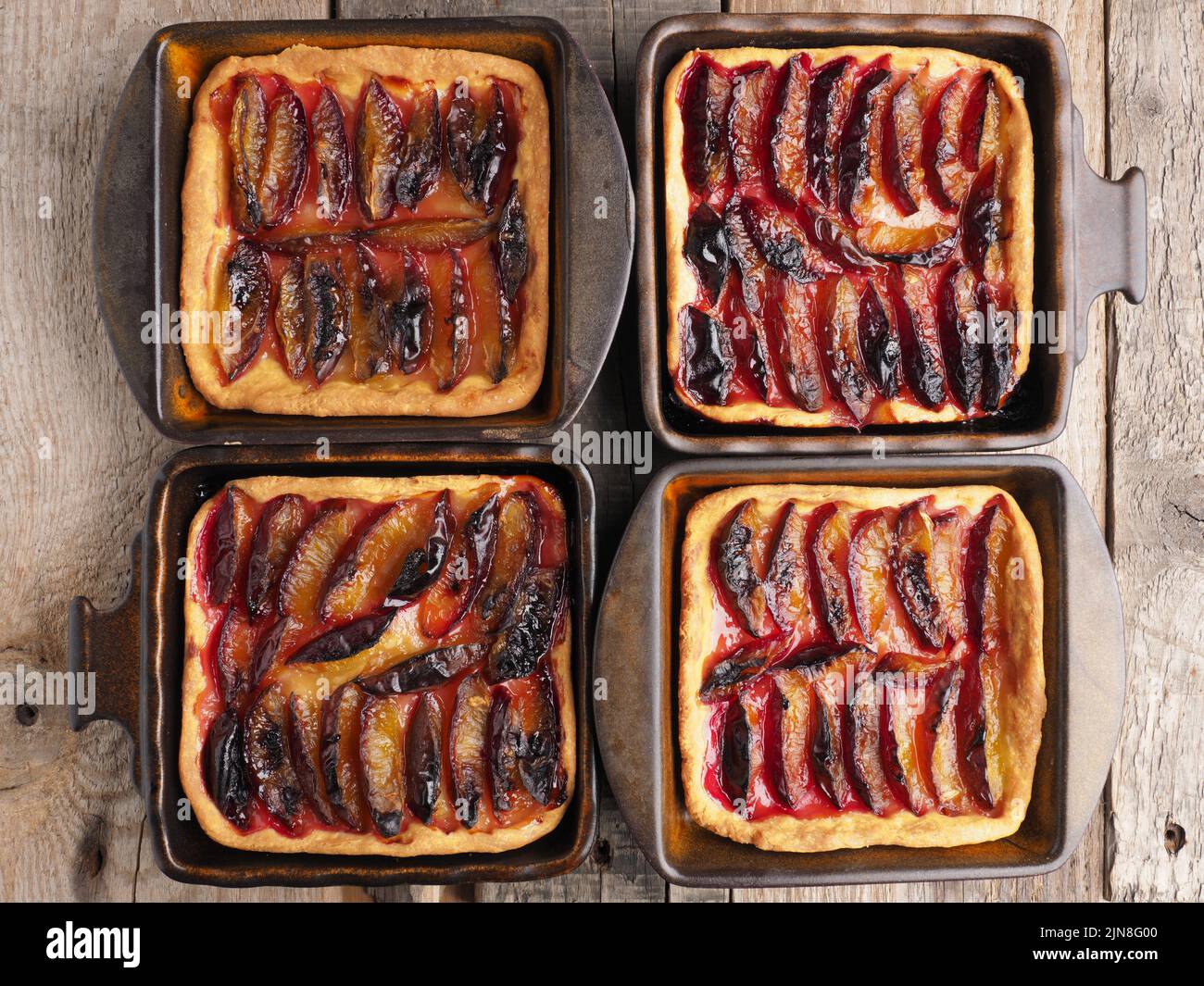 Gâteau aux prunes fraîchement cuit dans des bols en céramique sur une table de cuisine rustique, nourriture biologique, boulangerie de saison, vue d'en haut Banque D'Images