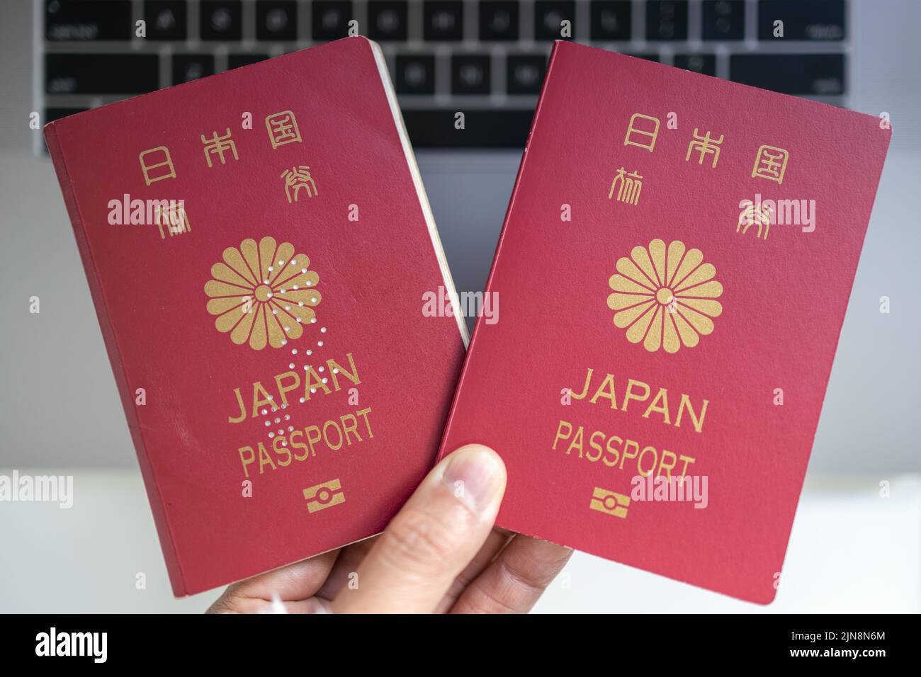 Deux passeports japonais, anciens et nouveaux et ordinateur portable fond donne l'idée de partir outre-mer Banque D'Images