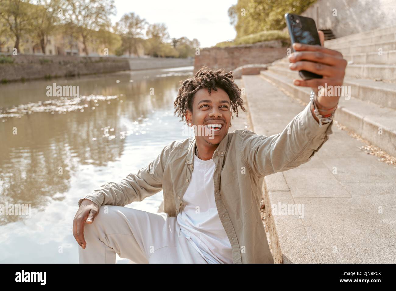 Un gars qui prend le selfie sur son smartphone près de l'eau Banque D'Images