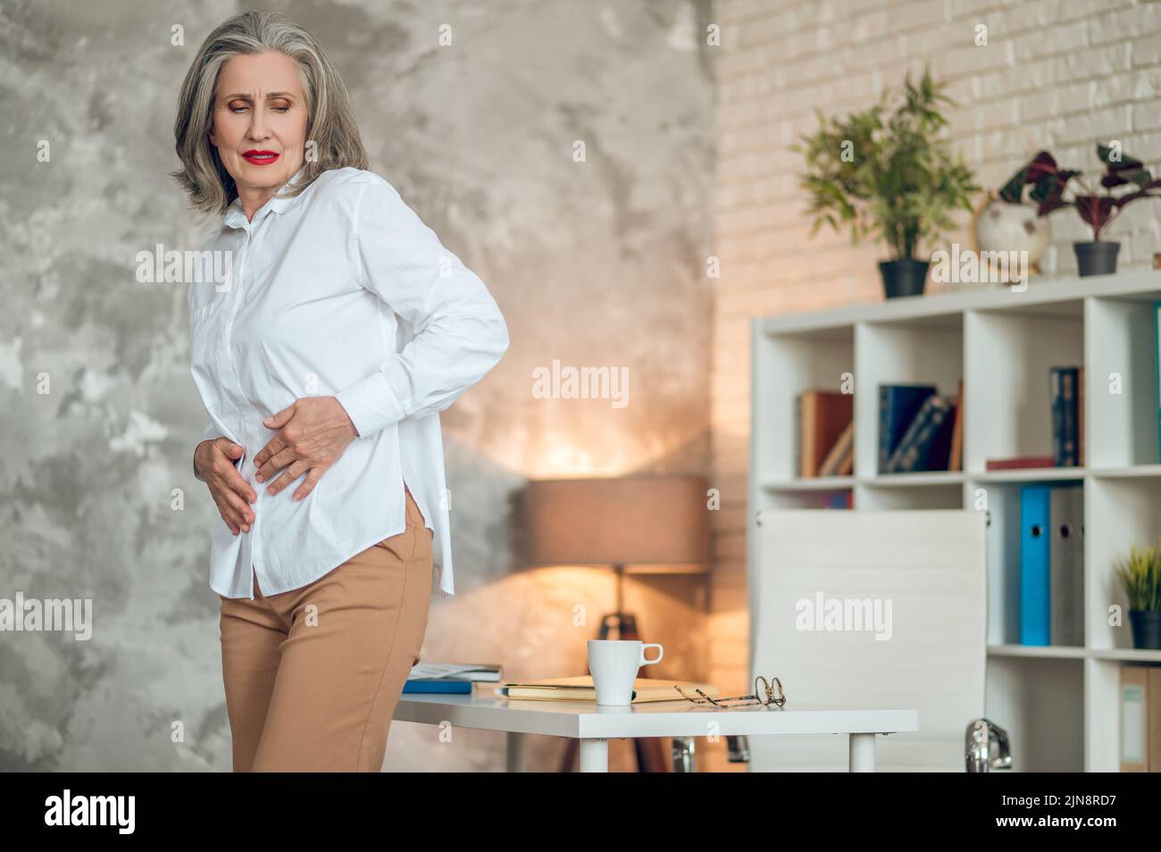 Bonne femme d'affaires qui souffre de douleurs à l'estomac Banque D'Images