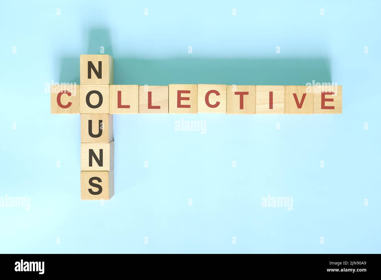 Concept de noms collectifs en grammaire anglaise. Jeu de mots croisés en bois posé sur fond bleu. Banque D'Images