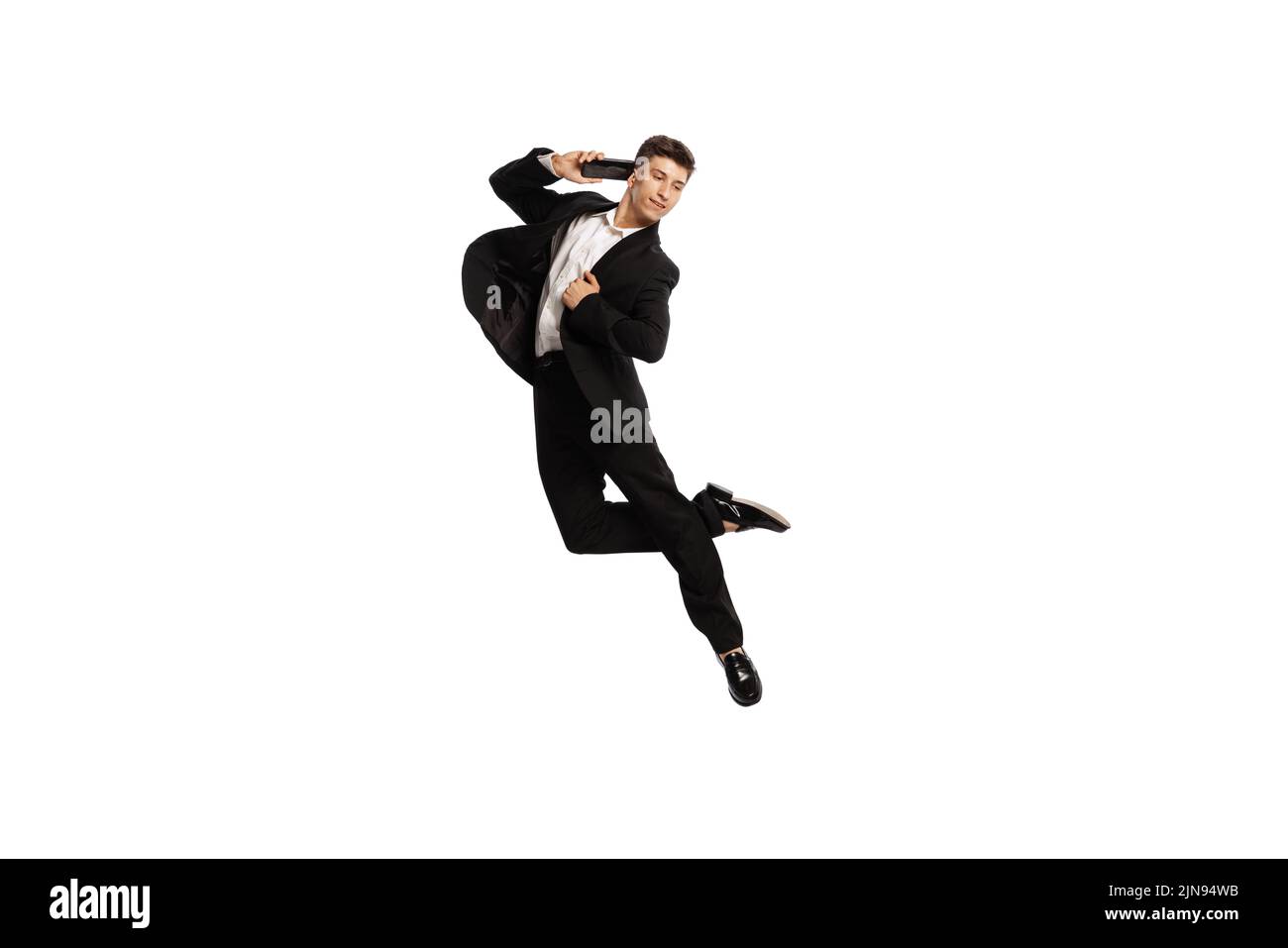 Portrait créatif d'un jeune employé de bureau en costume d'affaires parlant au téléphone isolé sur fond blanc. Finance, aspiration, business, concept de poste. Banque D'Images