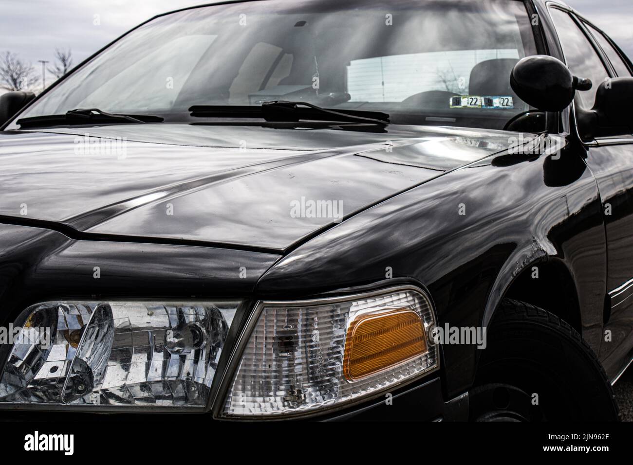 Un Ford Crown Victoria noir et son phare sous les rayons du soleil Banque D'Images